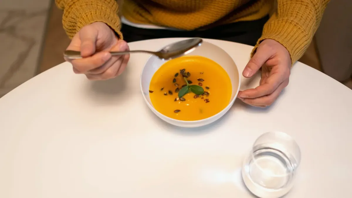 A dog eating a bowl of food mixed with pumpkin and vegetables