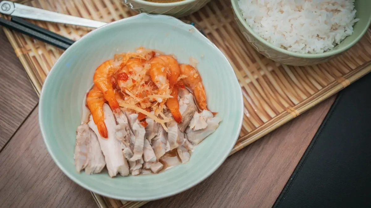 A small bowl of plain boiled chicken and white rice set on a kitchen floor