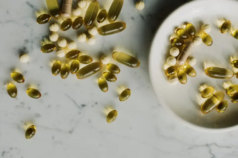 Amber fish oil softgel capsules spilled beside a measuring scoop