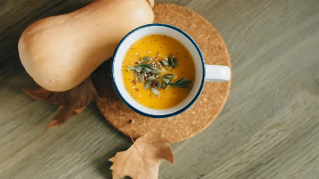 An open can of plain pumpkin puree beside a small jar of pumpkin powder and a measuring scoop