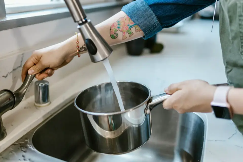 An owner refilling a dog's water bowl in a home kitchen