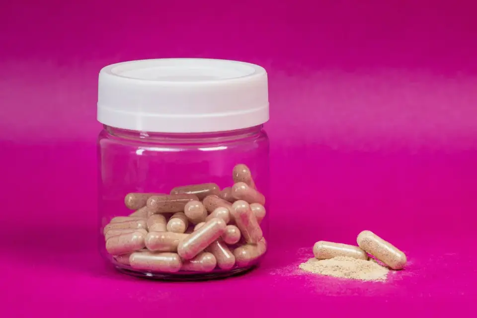 Ashwagandha root powder next to a jar of standardized extract capsules